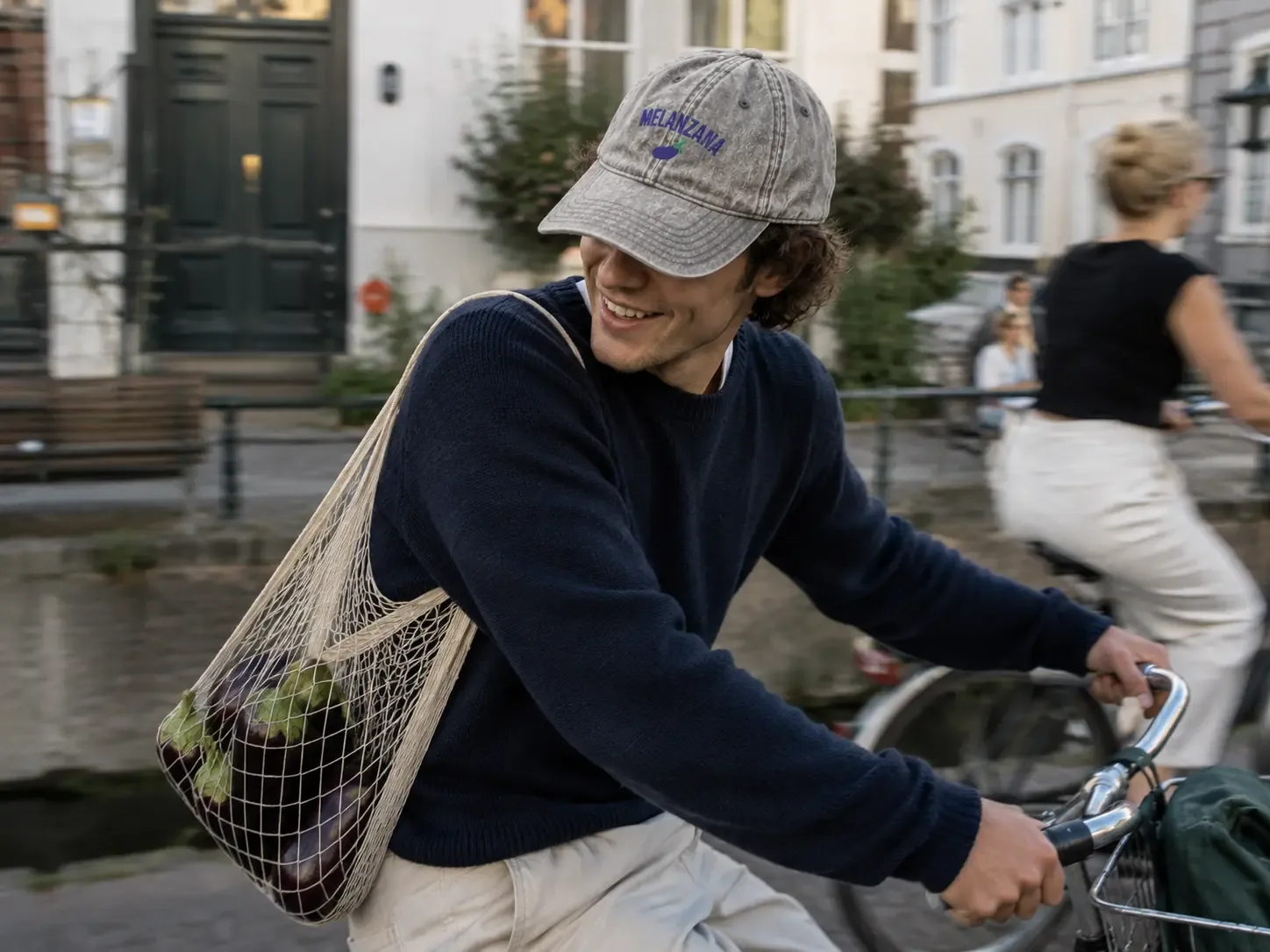 Man wearing the grey Melanzana cap while riding a bicycle